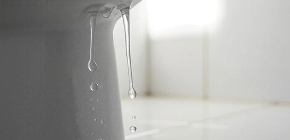 Plumber repairing a leaking faucet and toilet in a Conroe, TX bathroom